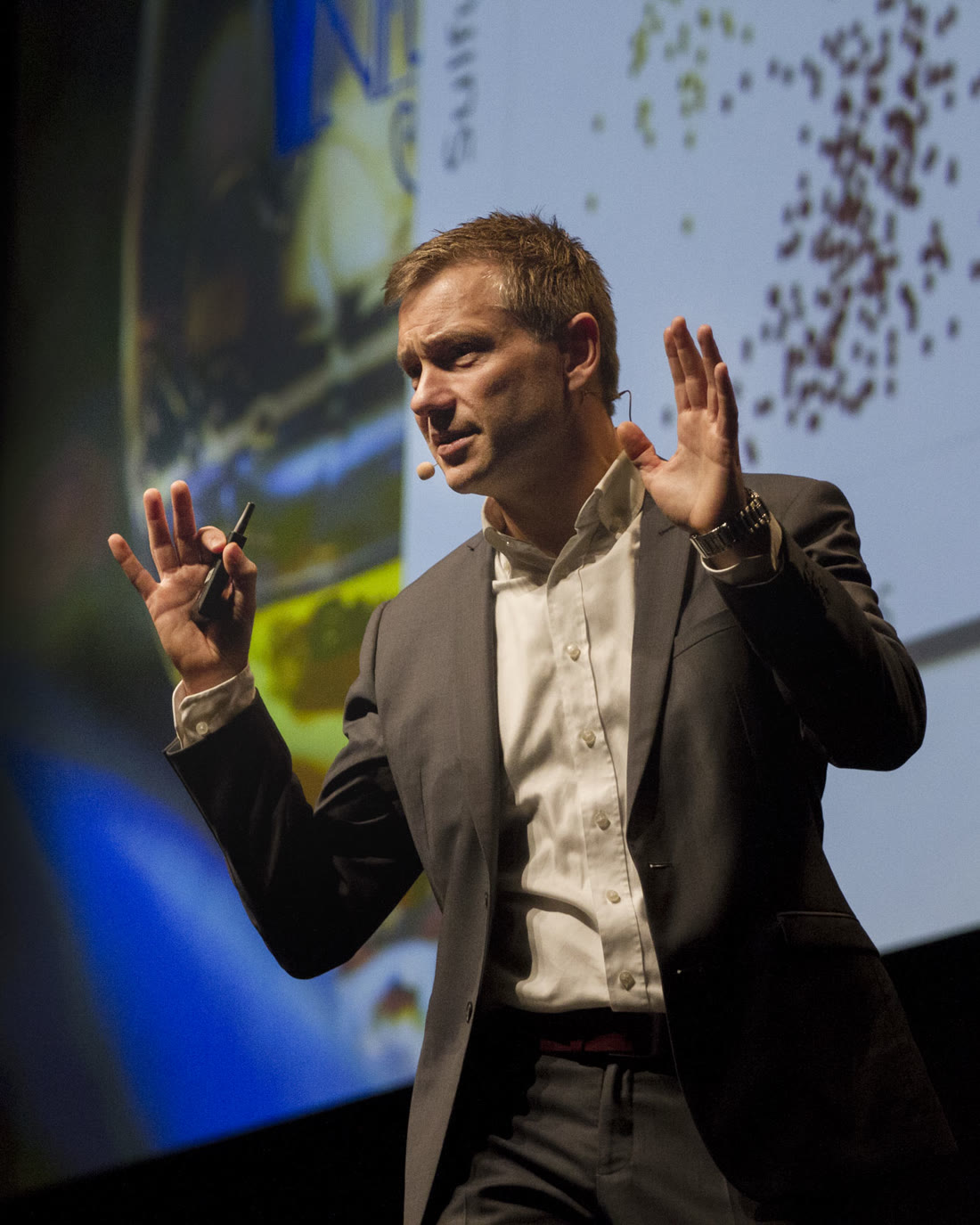Thomas Terney på scenen med headset og gestikulerende hænder foran et slide